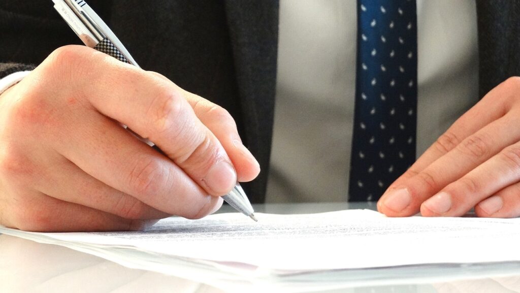 Image of man's hands signing documents | Angela Griffith Law